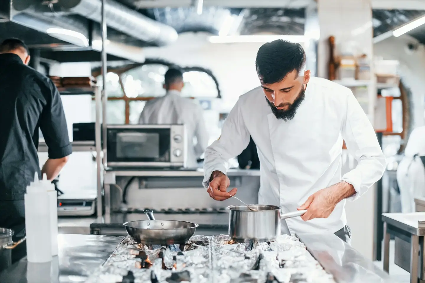 Chef in white uniform cooking food at kitchen. Busy day at work