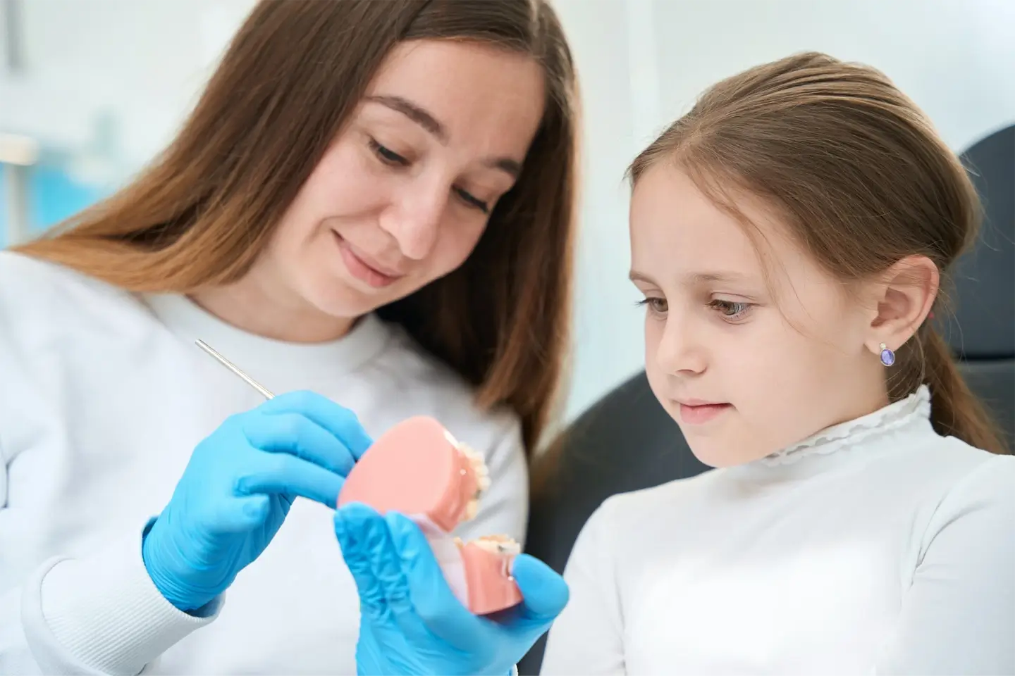 Pediatric dentist explaining teeth examination procedure to young patient