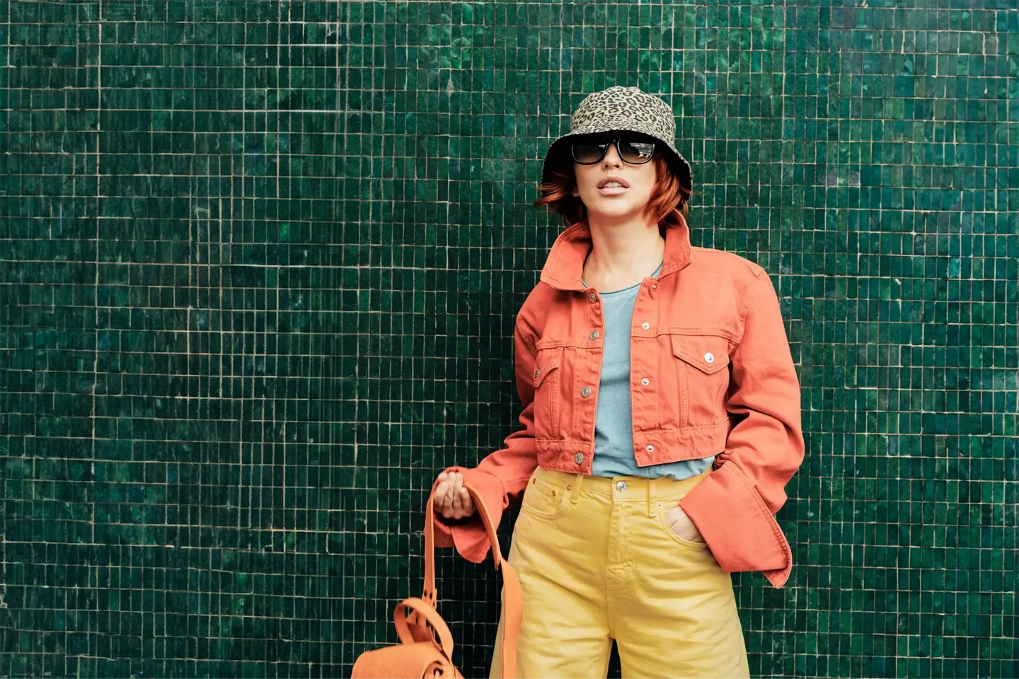 Hipster young woman in trendy peach color jacket, sun glasses posing. Color of the 2024 year.