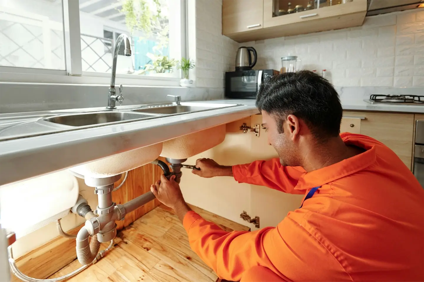 Plumber changing pipe under sink