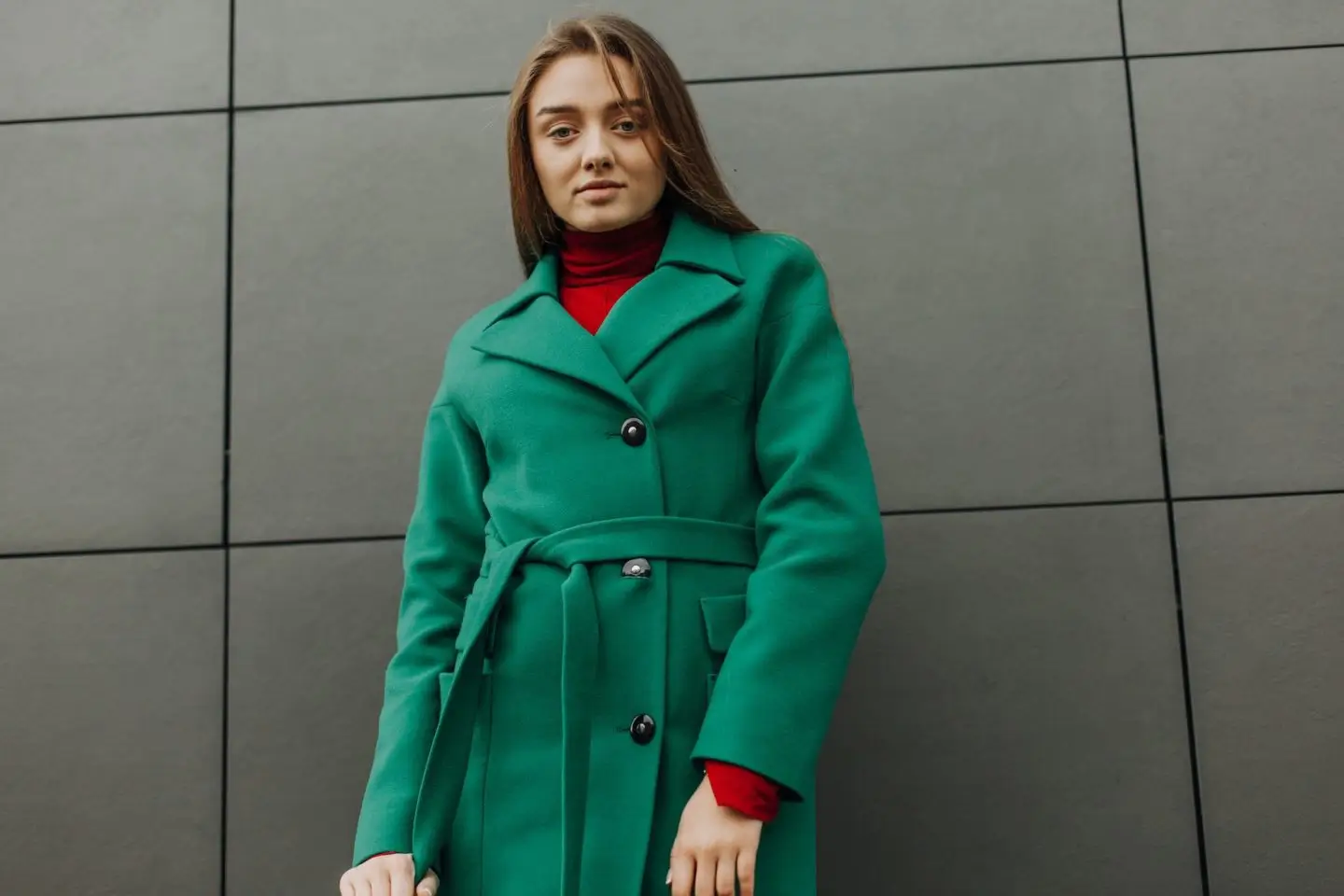 Beautiful fashion model in autumn green clothes on background. Sexy lady in elegant coat.